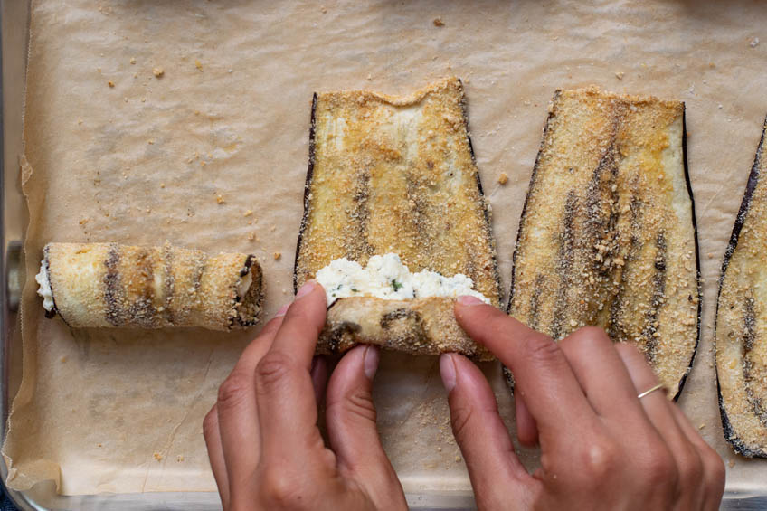 Eggplant being rolled up with ricotta filling