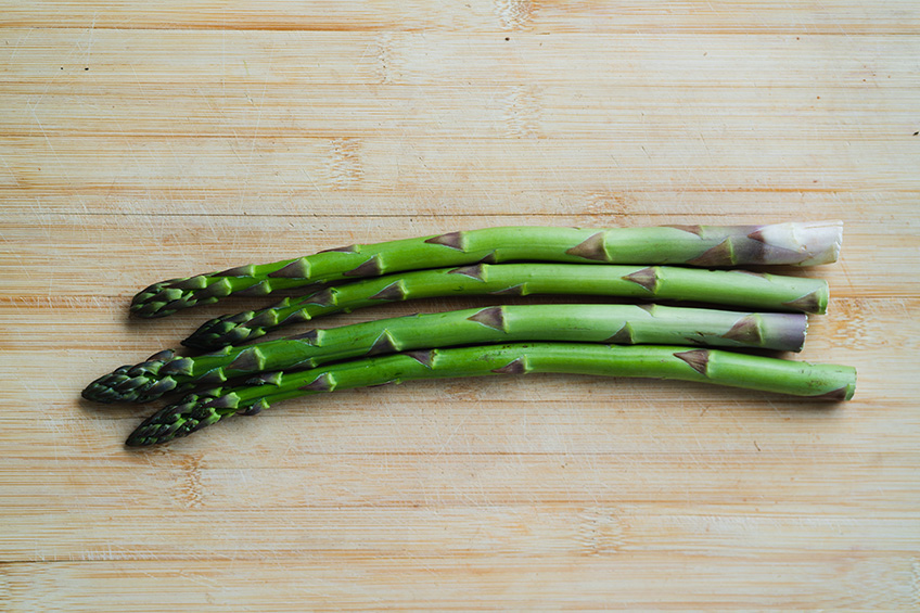 Asparagus stalks against a wooden backdrop.