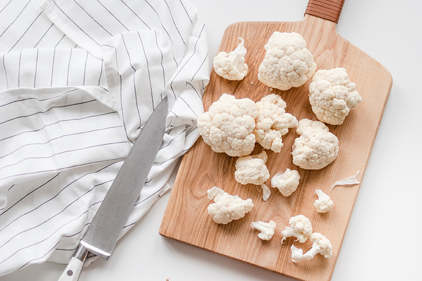 Cauliflower florets on a wooden cutting board