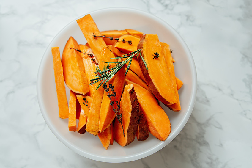 Sliced sweet potato in a bowl on light background.