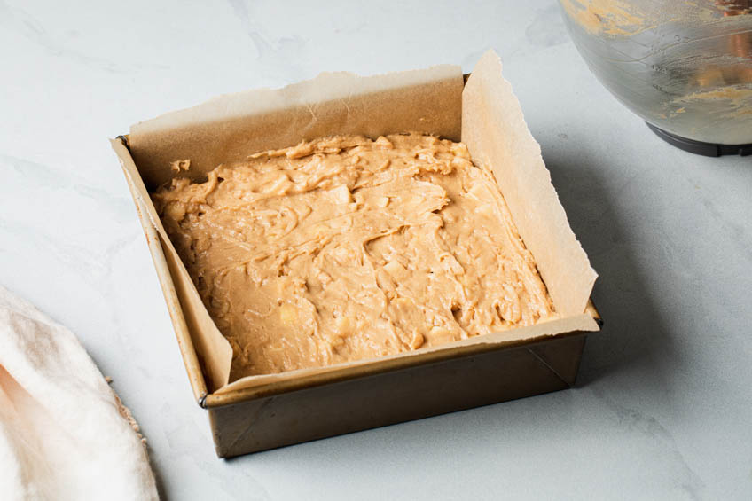 Apple cake batter in a square cake pan