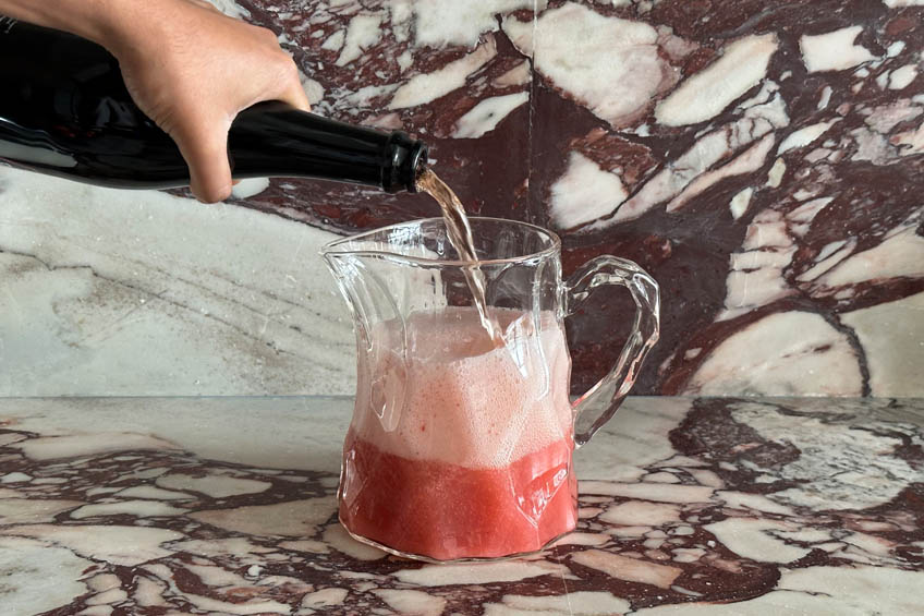 Bottle of sparkling rose being poured into pitcher