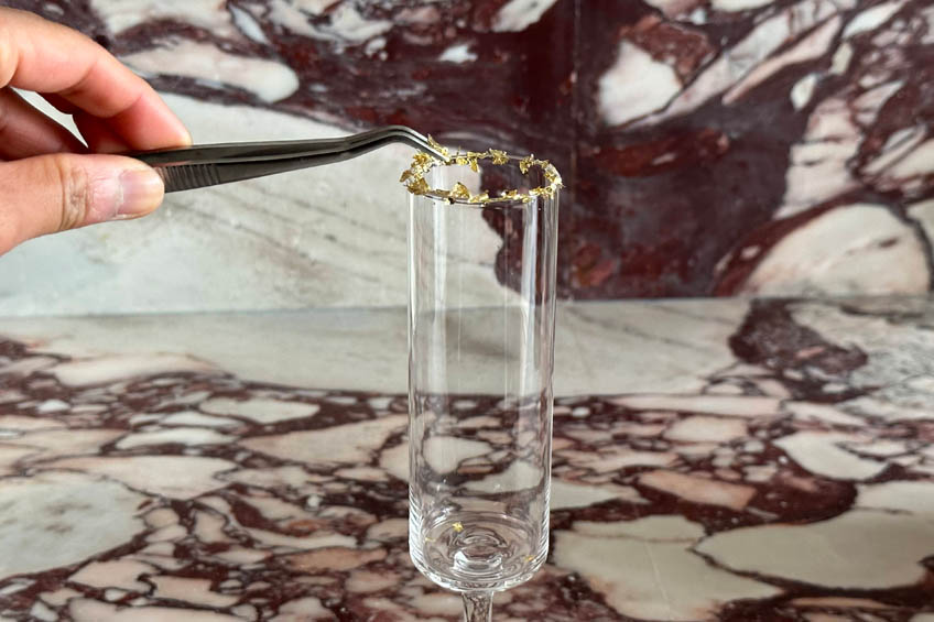 Champagne flutes being garnished with gold leaf