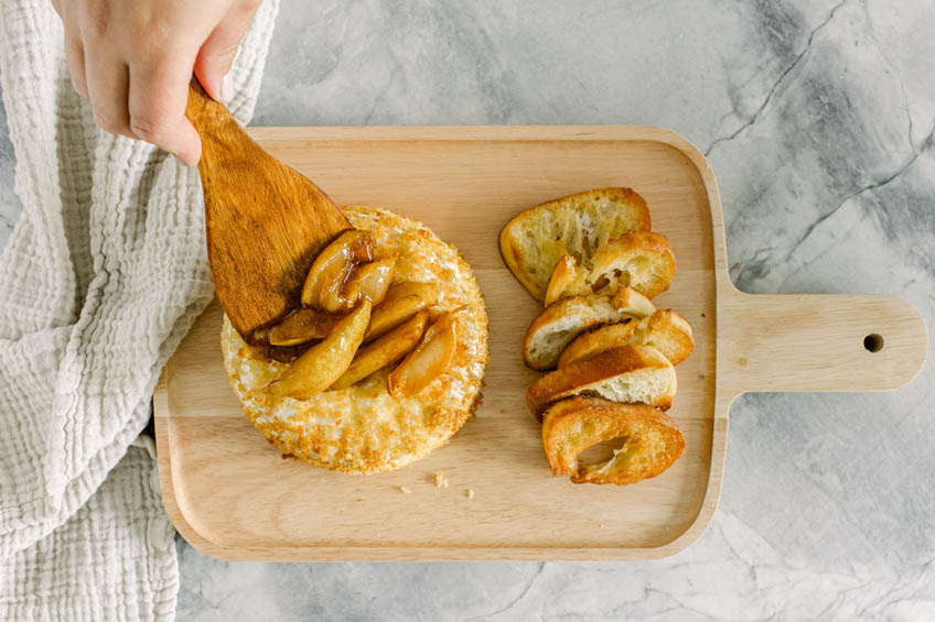 Air fried brie being topped with caramelized pears