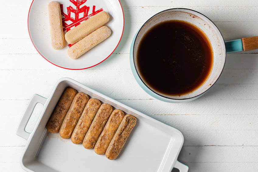 Cookies dipped in coffee lining the bottom of a baking dish