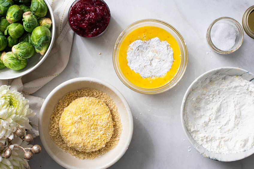 Turkey patties being dredged in egg, corn starch and panko.