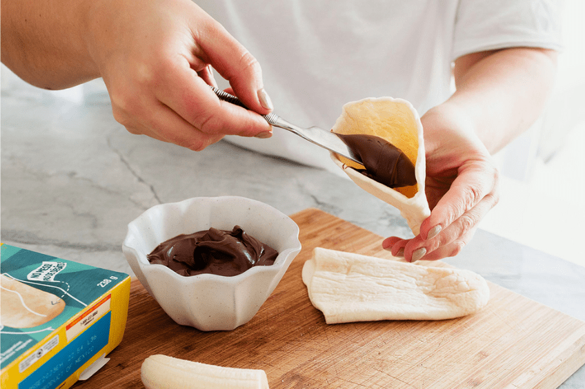 woman spreading chocolate spread on tortilla roll