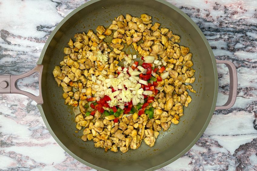 Chicken, aromatics and spices in a skillet