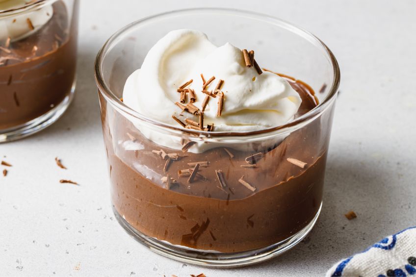 Closeup on a bowl of Earl Grey chocolate pudding topped with whipped cream and chocolate shavings