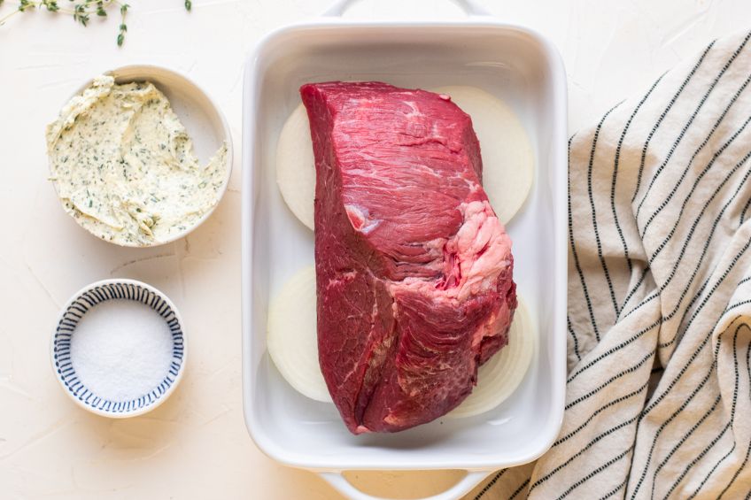 Beef placed on top of onions in baking dish