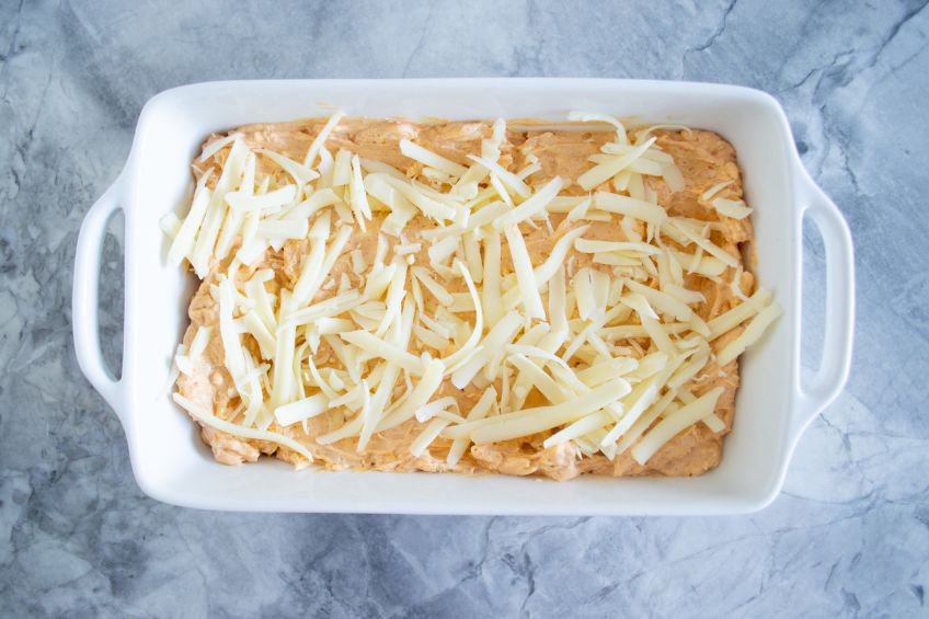 Nashville hot chicken dip in a casserole dish, topped with cheese