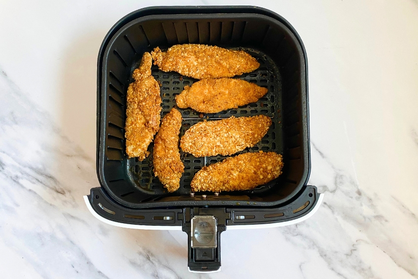 Cooked pretzel-crusted chicken tenders in air fryer basket