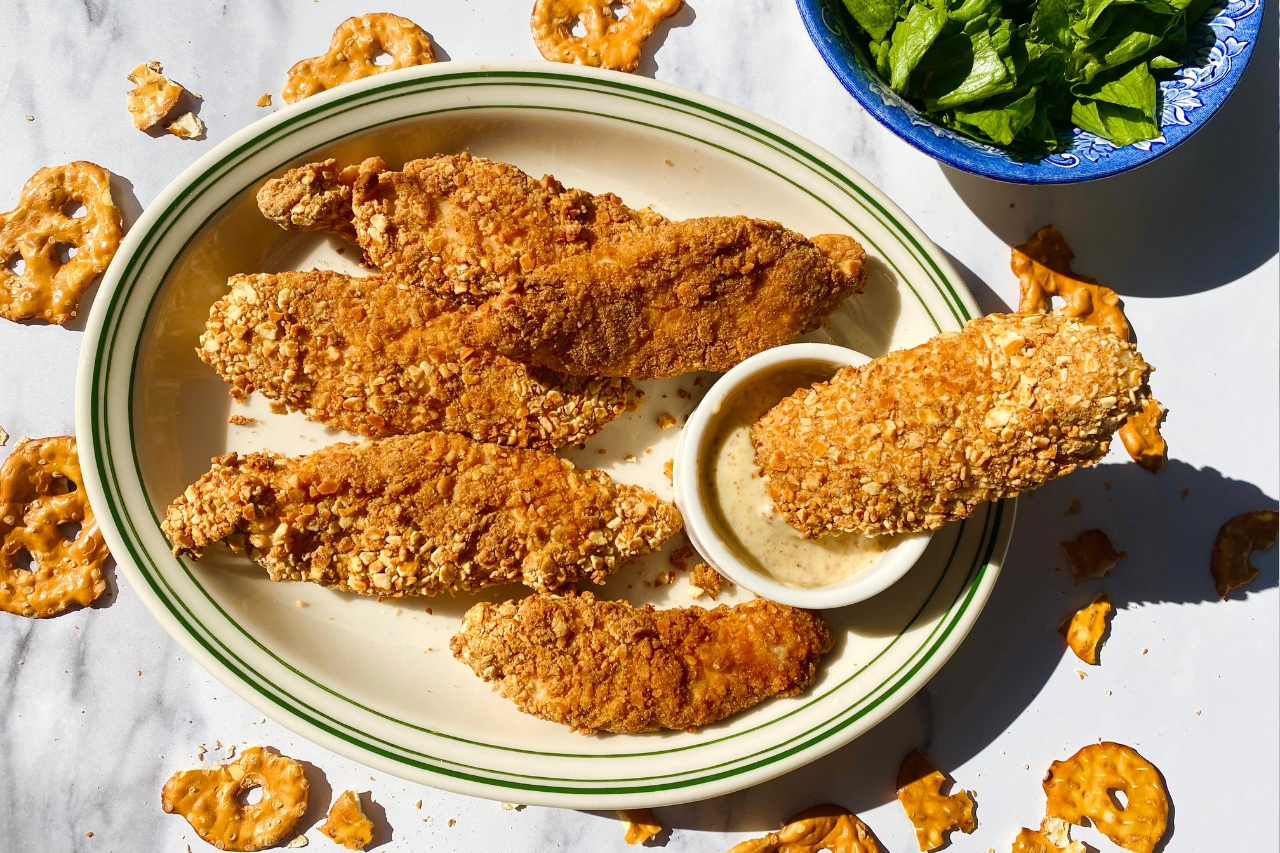 A plate of pretzel-crusted chicken tenders with honey mustard dip