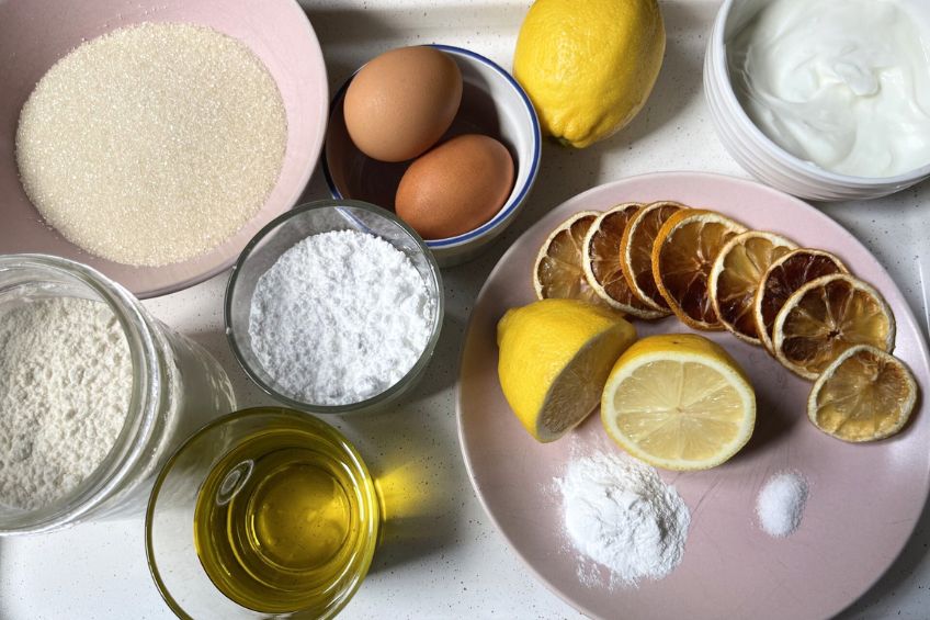 all the ingredients needed to make greek yogurt olive oil cake including eggs, flour, sugar ad baking powder