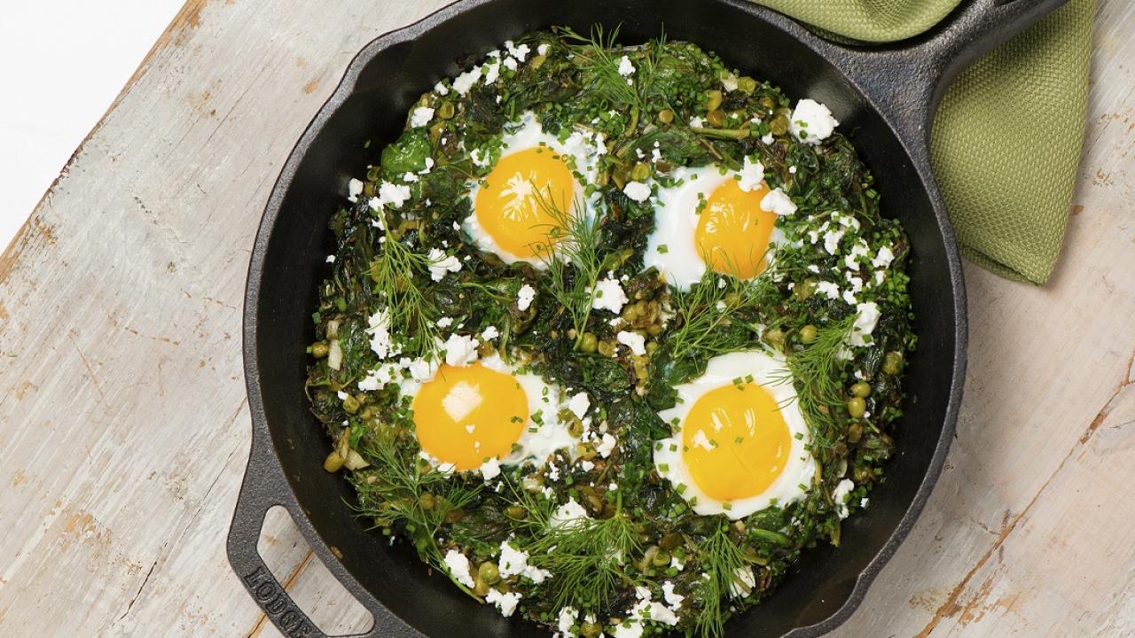 green shakshuka with eggs and feta cheese