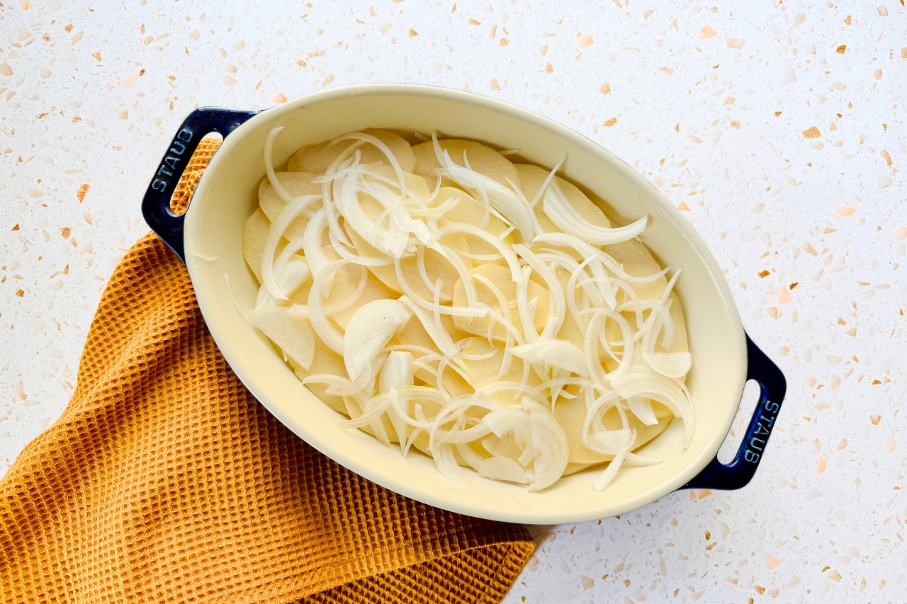 Thinly sliced potatoes and onions in baking dish