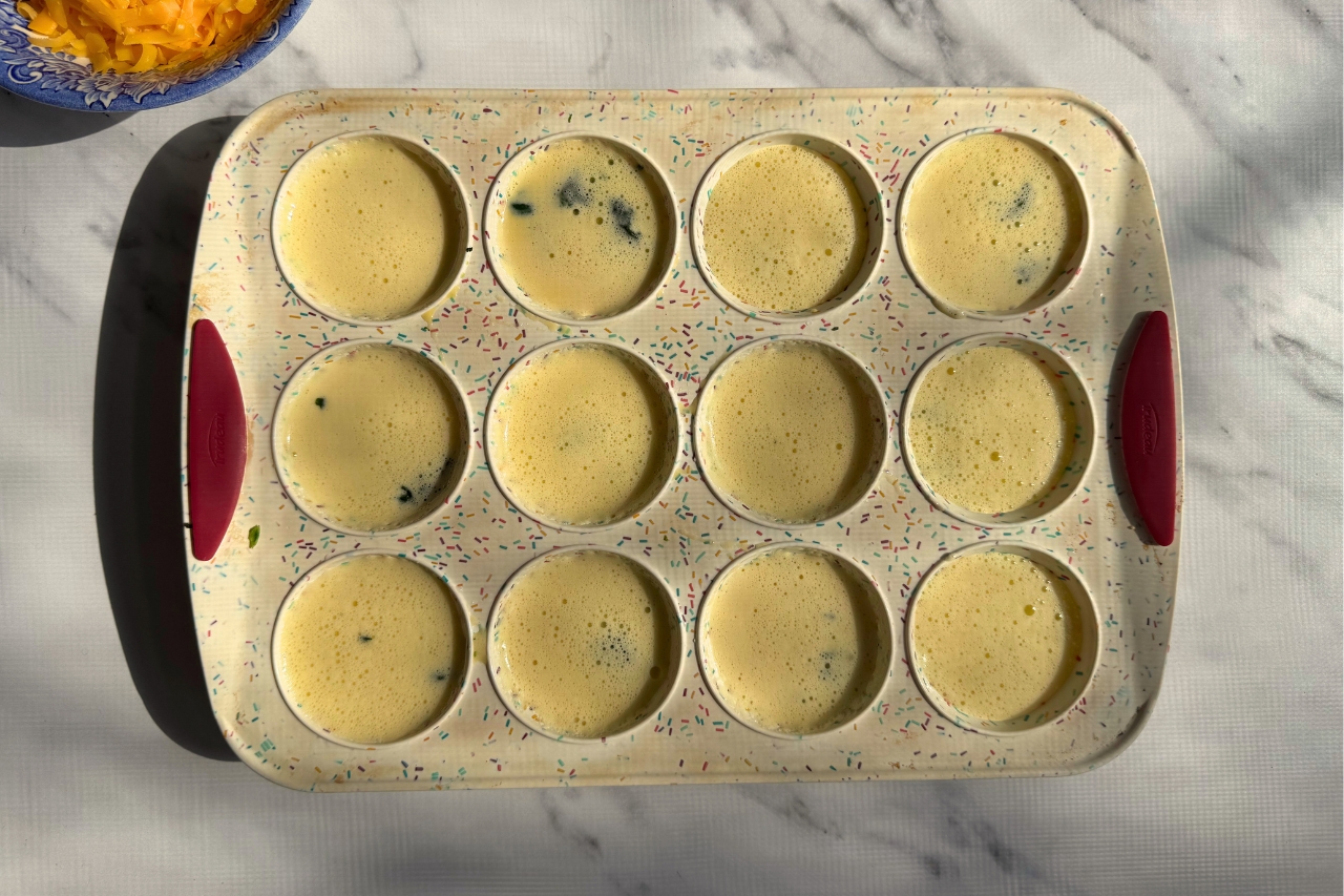 Uncooked cottage cheese egg bites in a muffin tray.