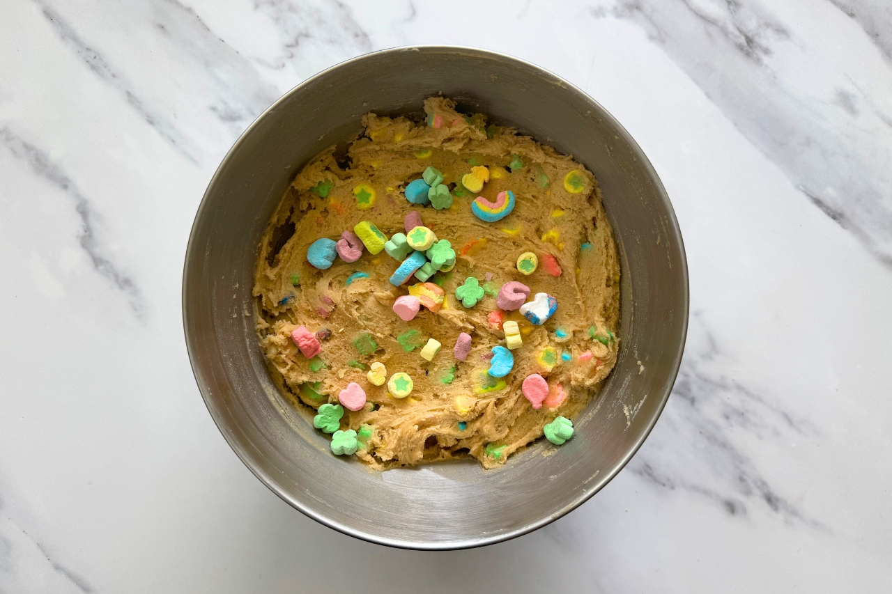 Cookie dough in a mixing bowl with lucky marshmallows