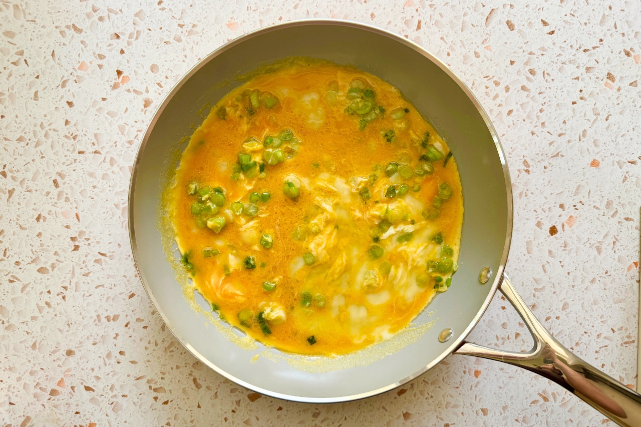 Eggs and green onions scrambling in a pan