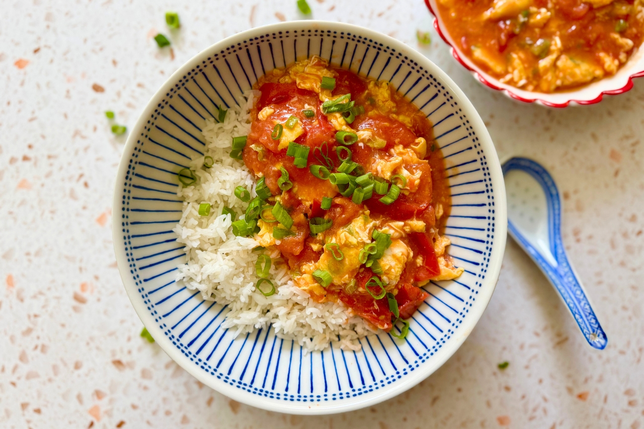 Chinese tomato egg stir fry over rice in a bowl