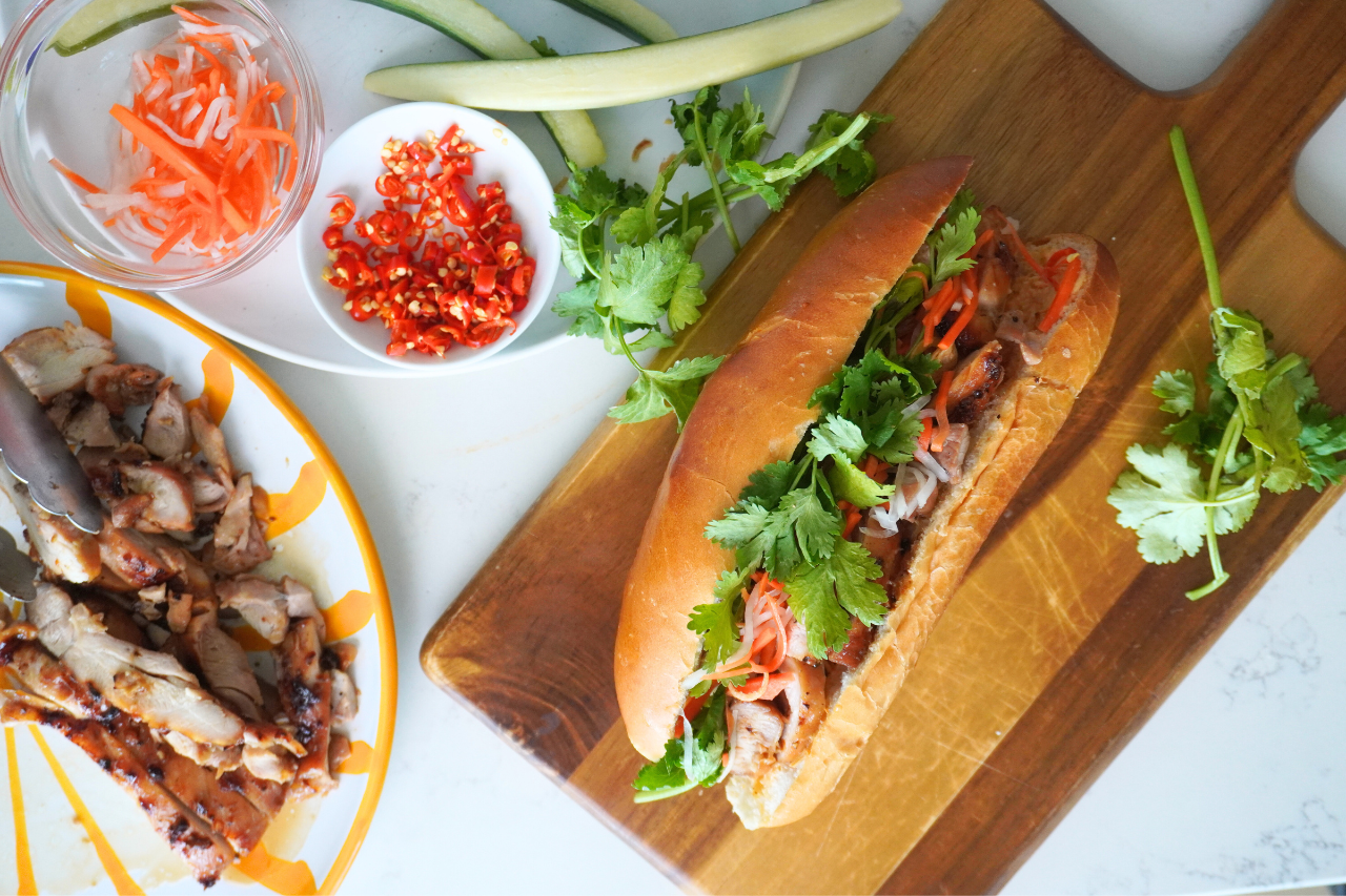 Chicken Banh Mi sandwich surrounded by veggies and extra chicken.