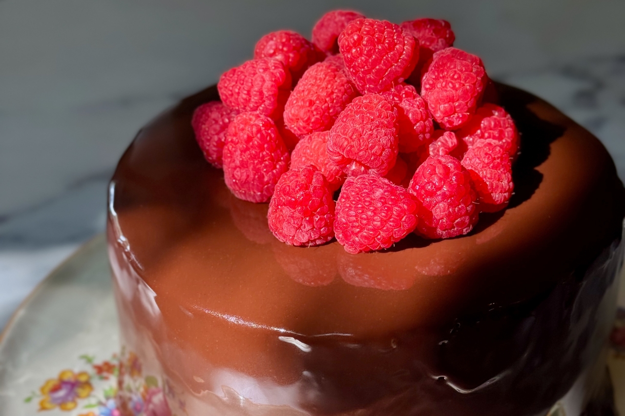 Chocolate mirror glaze cake with raspberry coulis
